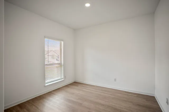 an empty room with chandelier fan and windows