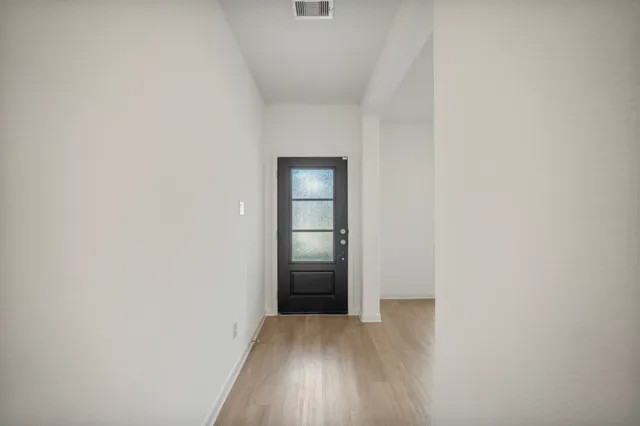 a view of an empty room with wooden floor and closet