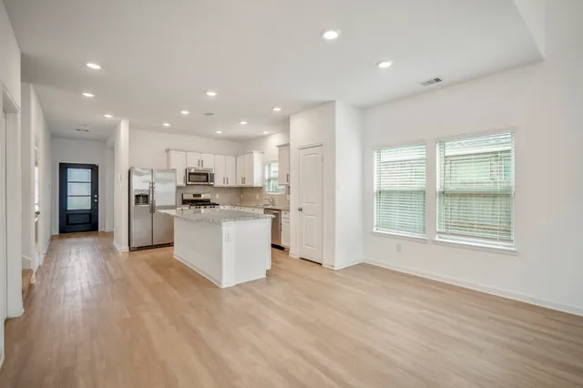 a view of kitchen with granite countertop refrigerator oven sink and white cabinets with wooden floor