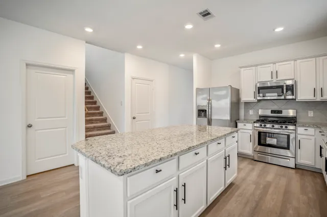 a kitchen with stainless steel appliances granite countertop a stove a sink and a refrigerator