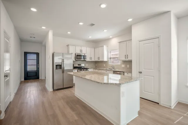 a large kitchen with stainless steel appliances granite countertop a large counter top a sink and a refrigerator