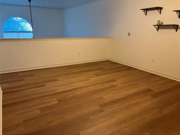 an empty room with wooden floor and chandelier fan
