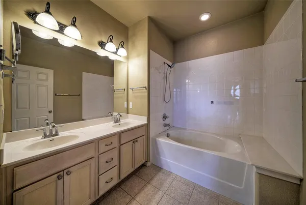 a bathroom with a tub a double vanity sink and a mirror