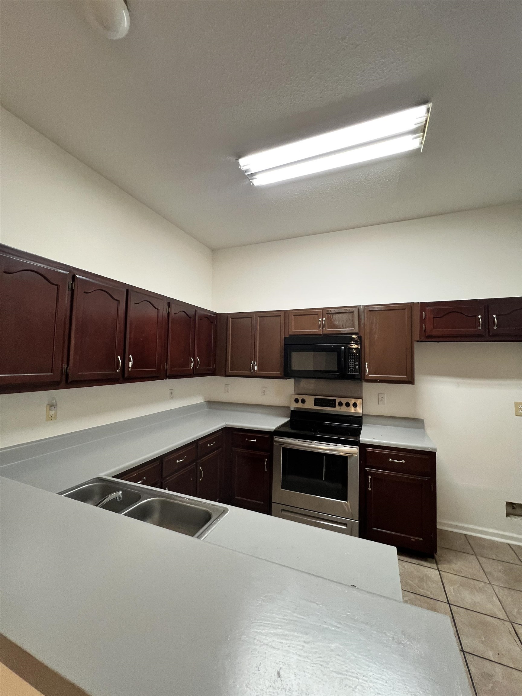 5760 Pecan Trace Memphis, TN 38135 - Photo 7 of 15 Kitchen with electric range, light tile patterned floors, light countertops, black microwave, and dark brown cabinets