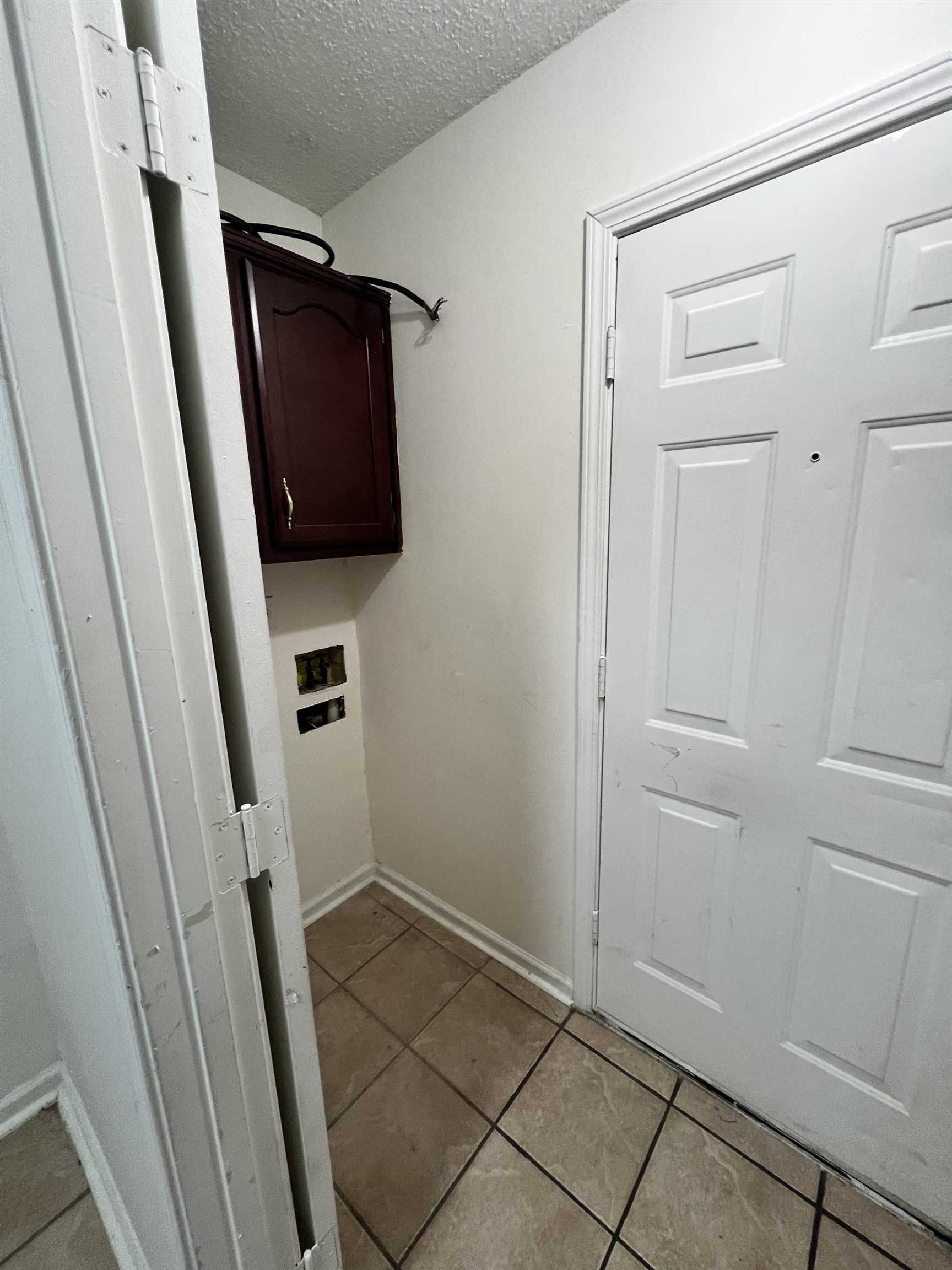 5760 Pecan Trace Memphis, TN 38135 - Photo 8 of 15 Washroom featuring a textured ceiling, light tile patterned flooring, cabinet space, and washer hookup