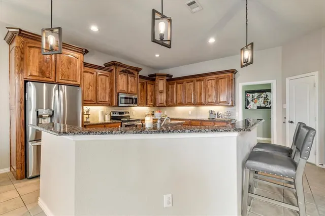 a kitchen with stainless steel appliances granite countertop a refrigerator a stove a sink dishwasher a dining table and chairs with wooden floor