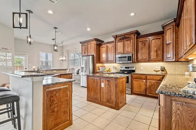 a kitchen with stainless steel appliances granite countertop a stove top oven a sink dishwasher and a refrigerator