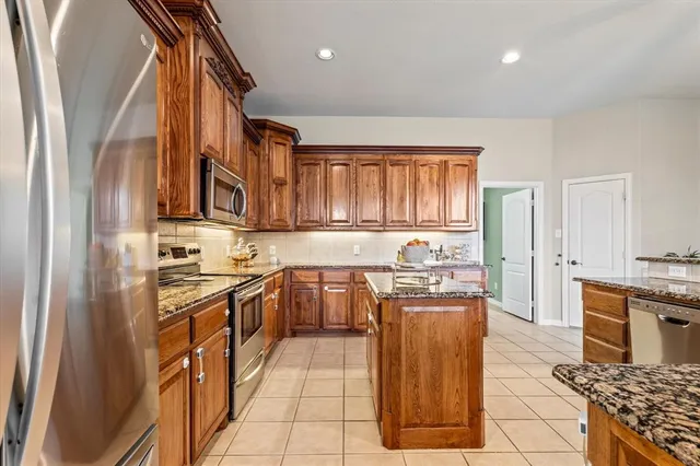 a kitchen with stainless steel appliances granite countertop a stove a sink dishwasher and a refrigerator