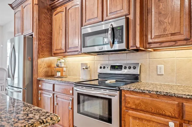a kitchen with stainless steel appliances granite countertop a stove a sink and a microwave