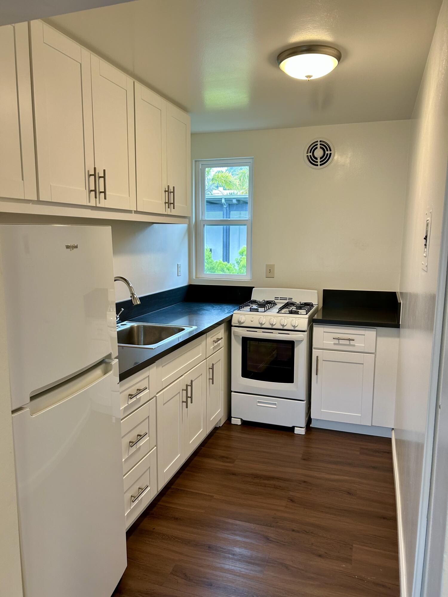 47 Ocean View Avenue, Unit 14 Santa Barbara, CA 93103 - Photo 6 of 9 a kitchen with granite countertop white cabinets and wooden floor