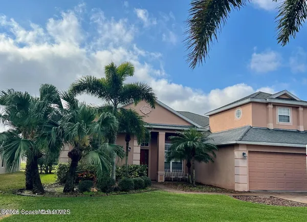 a view of a white house with a big yard and potted plants