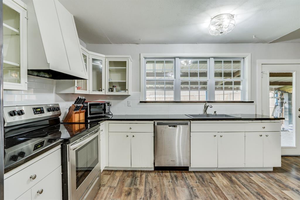 a kitchen with granite countertop cabinets stainless steel appliances a sink and a window