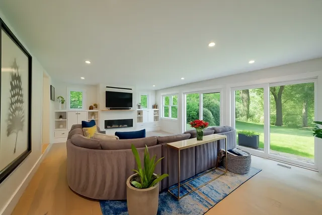a living room with furniture fireplace and a large window