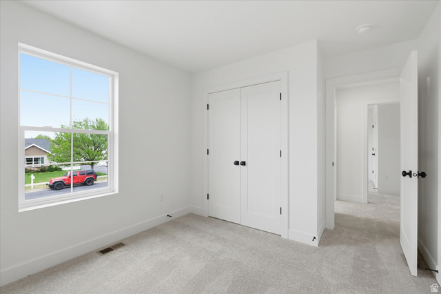 844 North 400 West Logan, UT 84321 - Photo 27 of 43 Bright interior room featuring a large window, light-toned carpeting, white walls, and a double-door closet with black hardware