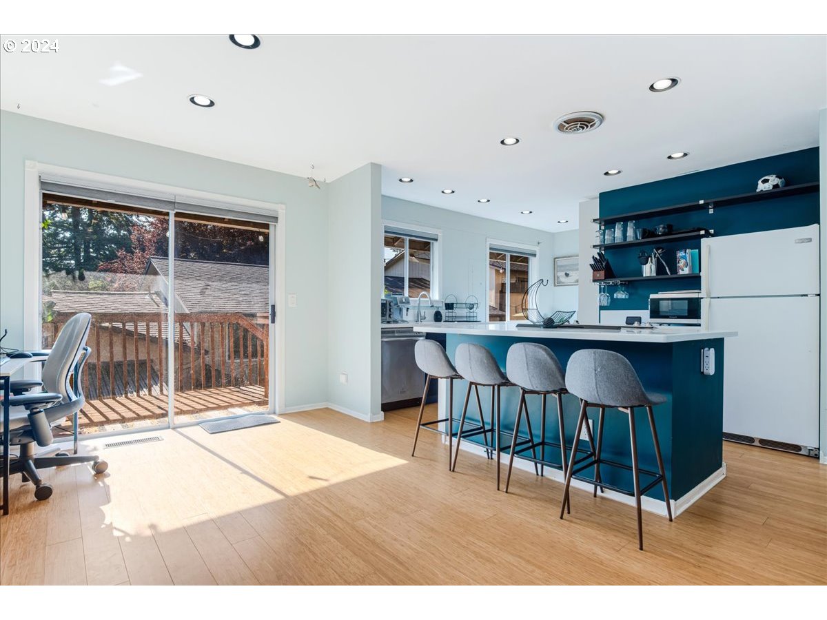 2675 Southwest Spring Garden Street Portland, OR 97219 - Photo 13 of 31 a open kitchen with stainless steel appliances kitchen island granite countertop a refrigerator a stove a sink dishwasher and white cabinets with wooden floor