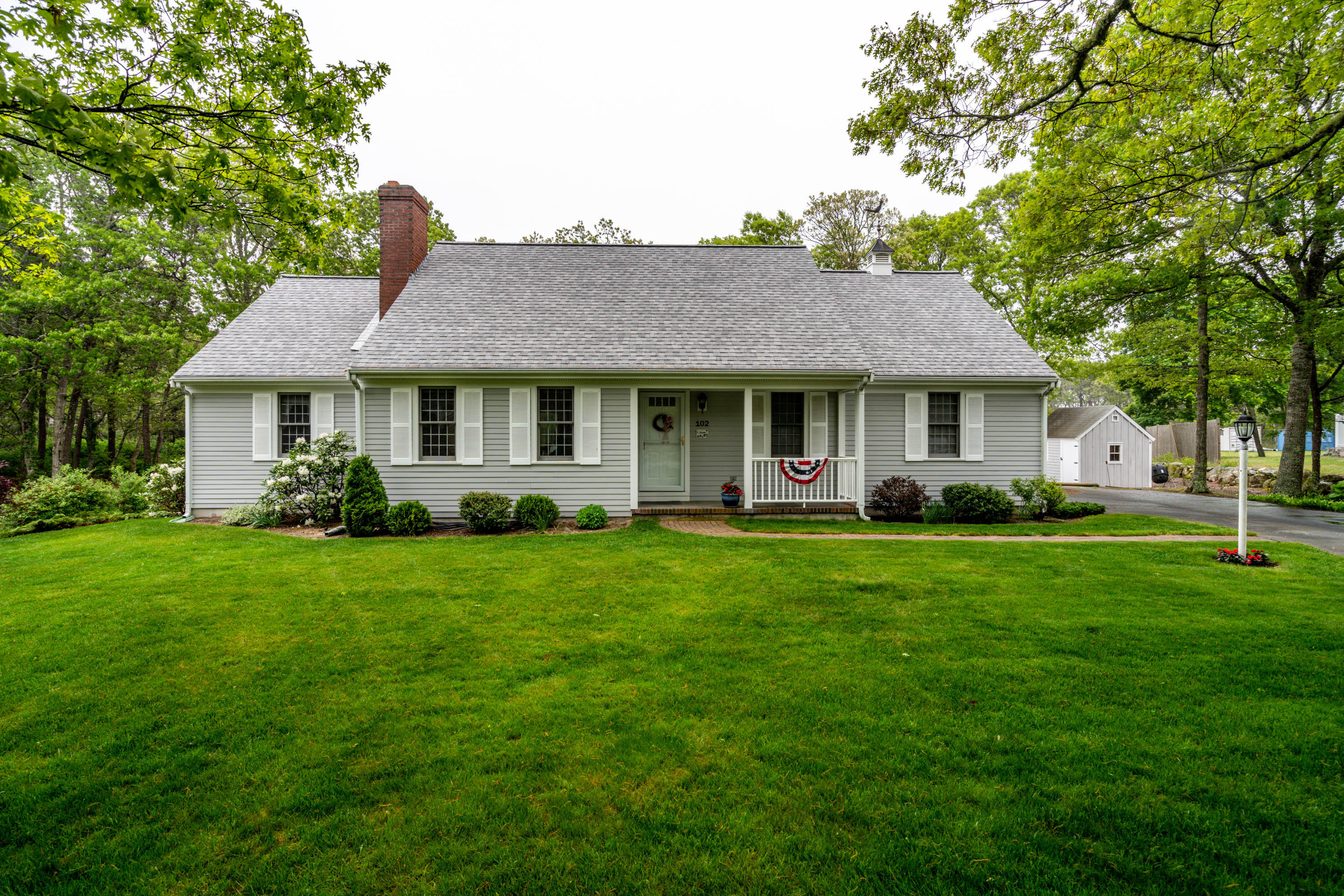 102 Long Hill Road Dennis, MA 02638 - Photo 2 of 24 a front view of a house with a yard and trees