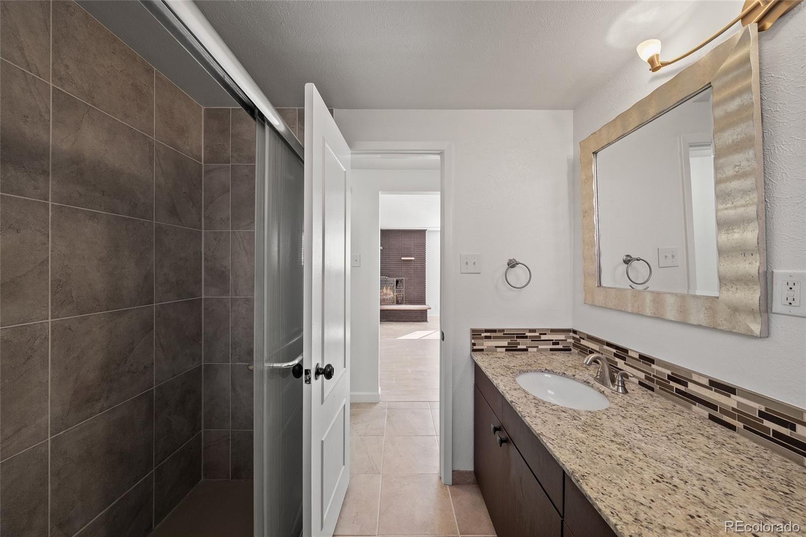3045 Stuart Street Denver, CO 80212 - Photo 28 of 41 a bathroom with a granite countertop sink a mirror and a shower
