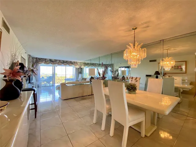 a view of a dining room and livingroom with furniture wooden floor a chandelier