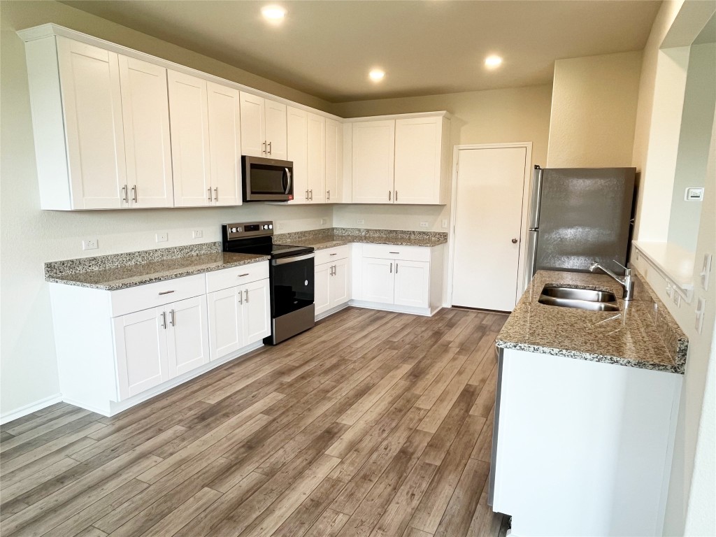 54 Pacific Loon Street Leander, TX 78641 - Photo 6 of 27 a kitchen with granite countertop white cabinets and white appliances