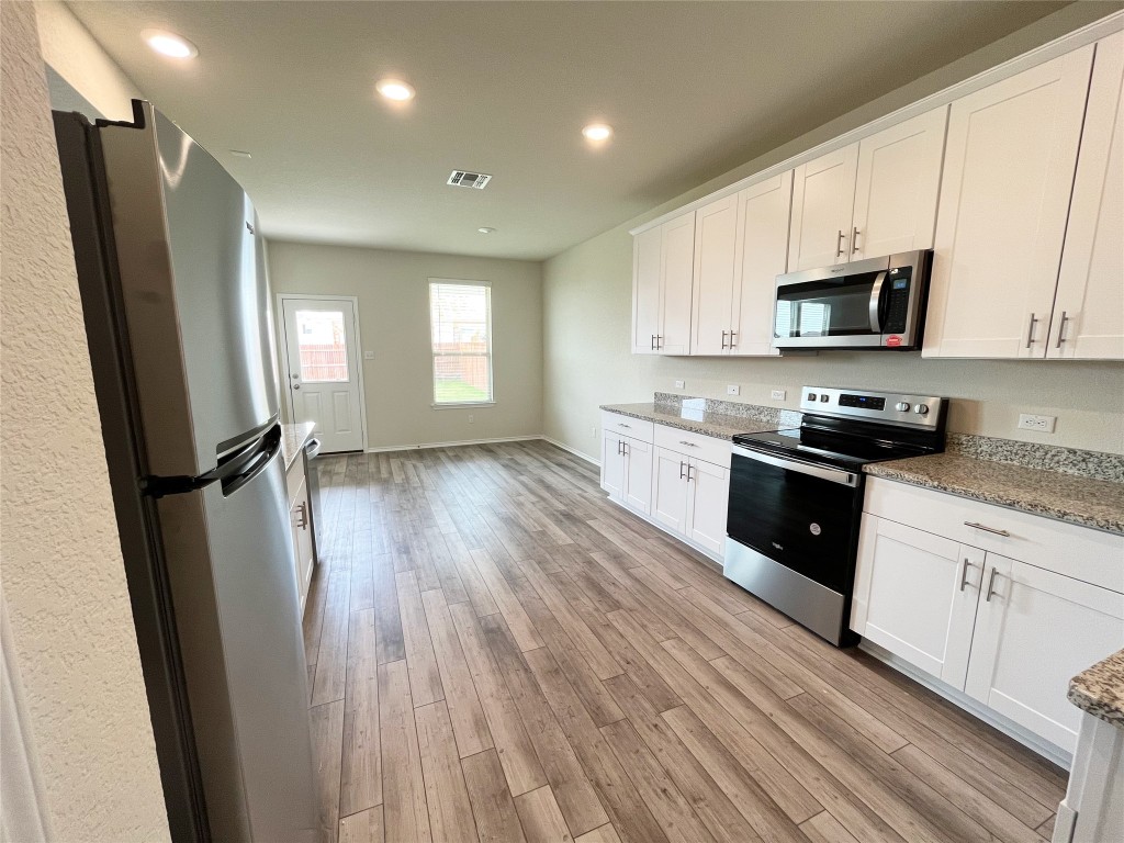 54 Pacific Loon Street Leander, TX 78641 - Photo 8 of 27 a kitchen with a sink a refrigerator a window and cabinets