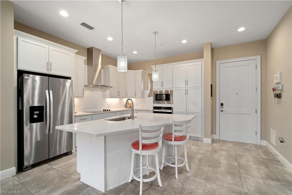 a kitchen with stainless steel appliances kitchen island granite countertop a table chairs refrigerator and microwave