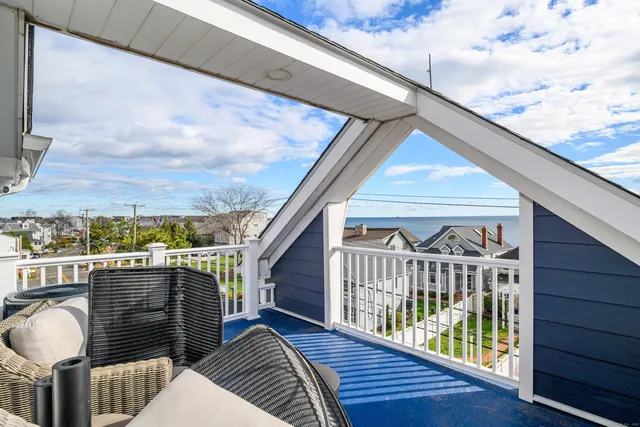 a balcony with wooden floor stairs and outdoor seating