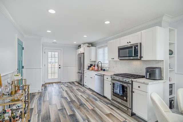 a kitchen with stainless steel appliances a white stove top oven a sink dishwasher and a refrigerator with wooden floor