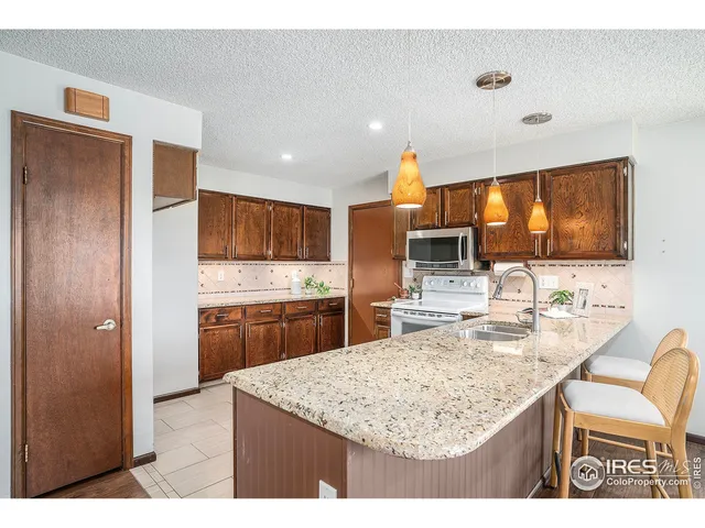 a kitchen with kitchen island granite countertop wooden cabinets and refrigerator