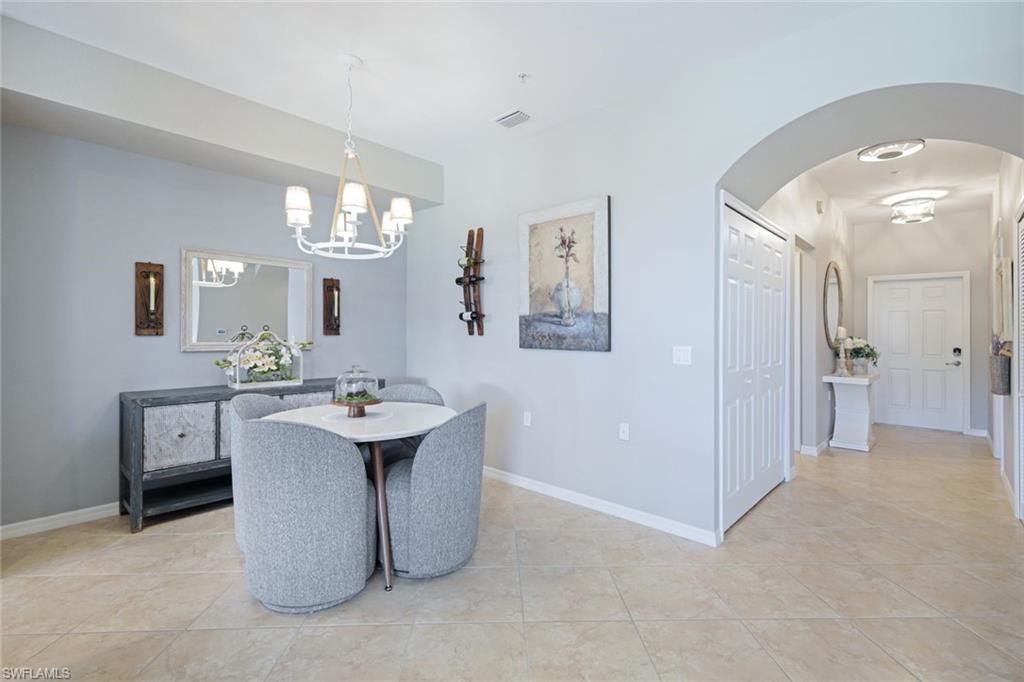 10329 Heritage Bay Boulevard, Unit 1641 Naples, FL 34120 - Photo 14 of 22 Dining space featuring a chandelier, light tile patterned floors, arched walkways, and baseboards
