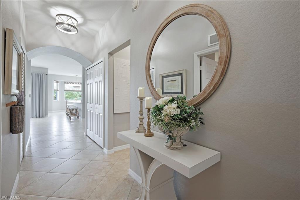 10329 Heritage Bay Boulevard, Unit 1641 Naples, FL 34120 - Photo 2 of 22 Hall featuring arched walkways, light tile patterned floors, and baseboards
