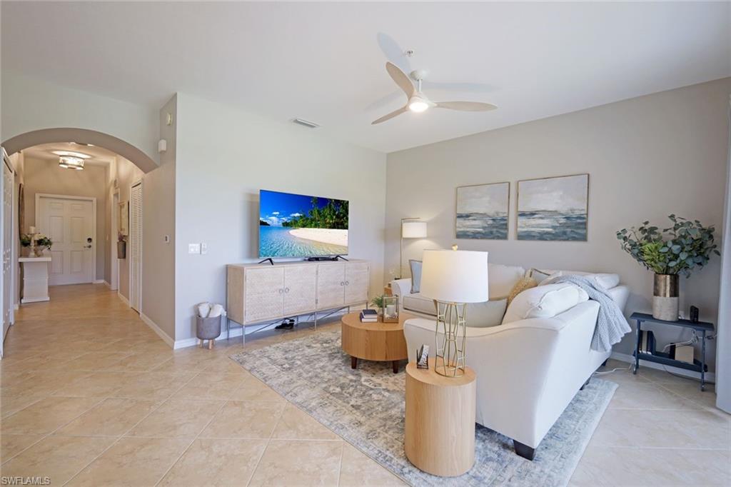 10329 Heritage Bay Boulevard, Unit 1641 Naples, FL 34120 - Photo 4 of 22 Living room featuring arched walkways, ceiling fan, light tile patterned floors, and baseboards