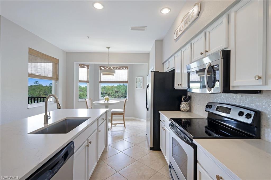 10329 Heritage Bay Boulevard, Unit 1641 Naples, FL 34120 - Photo 8 of 22 Kitchen featuring stainless steel appliances, a sink, light countertops, white cabinets, and decorative backsplash