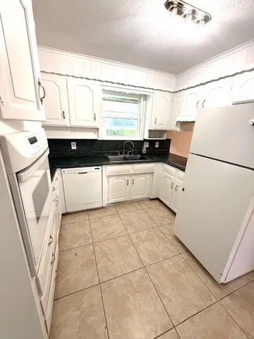 a kitchen with a sink a stove top oven and cabinets