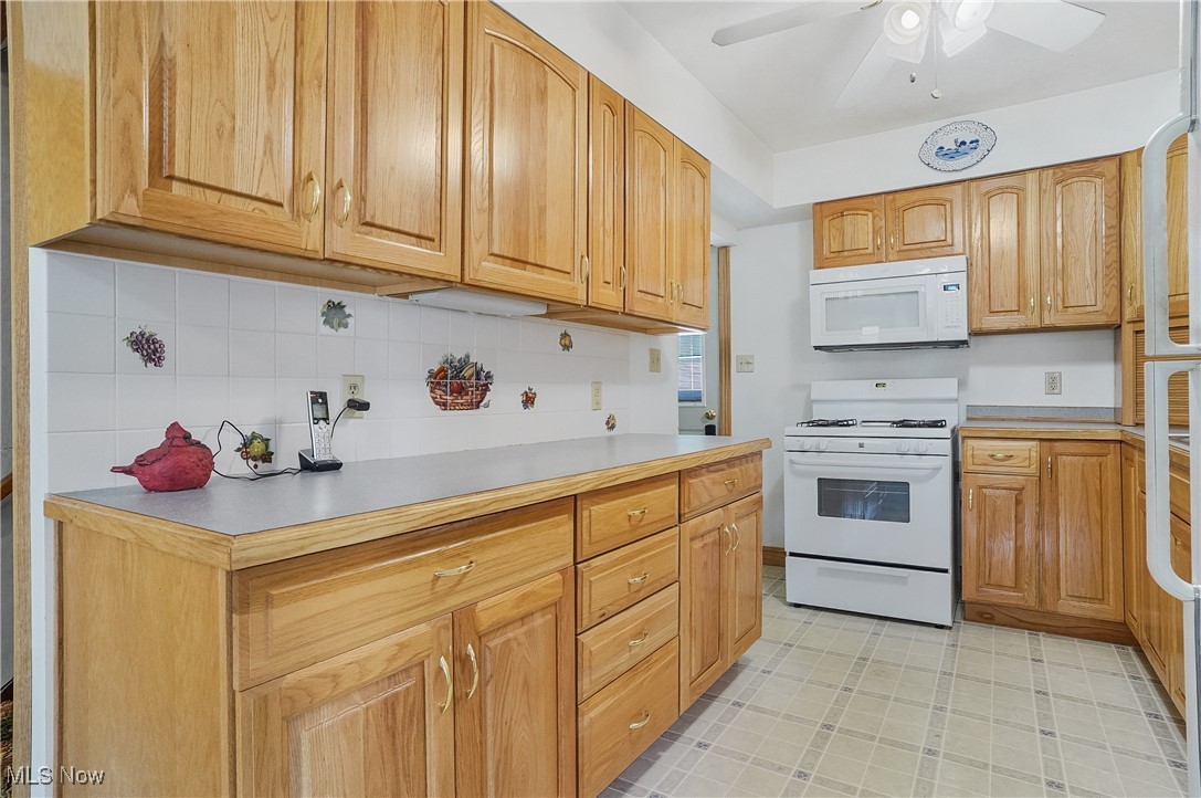 2809 McElwain Road Akron, OH 44312 - Photo 20 of 38 Kitchen with white appliances, light countertops, decorative backsplash, and ceiling fan