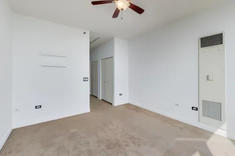 an empty room with a ceiling fan and closet area