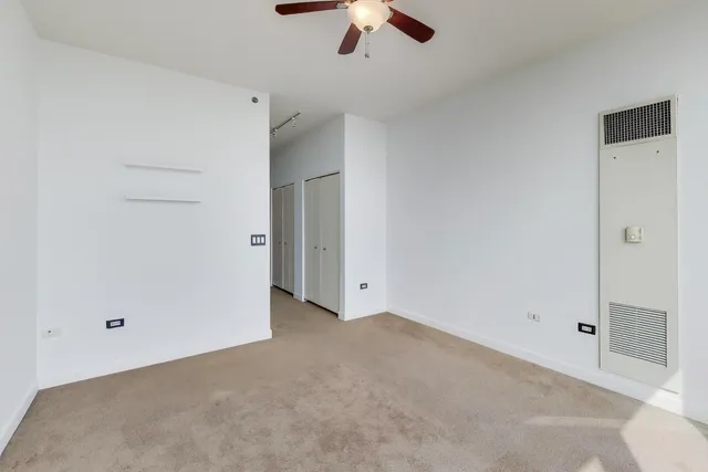 an empty room with a ceiling fan and closet area