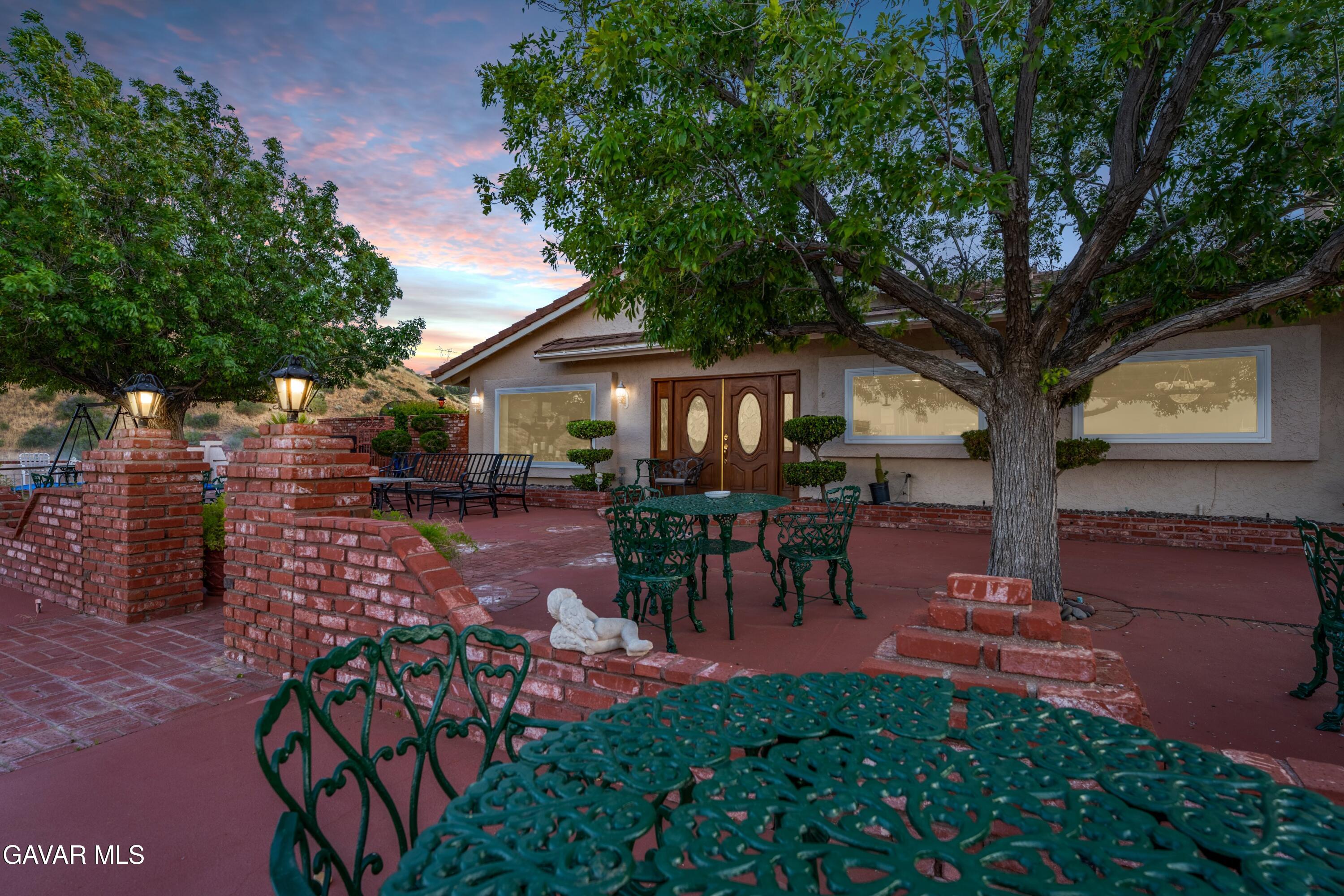 5801 Hacienda Ranch Road Palmdale, CA 93551 - Photo 4 of 69 a view of a patio with table and chairs potted plants and large tree