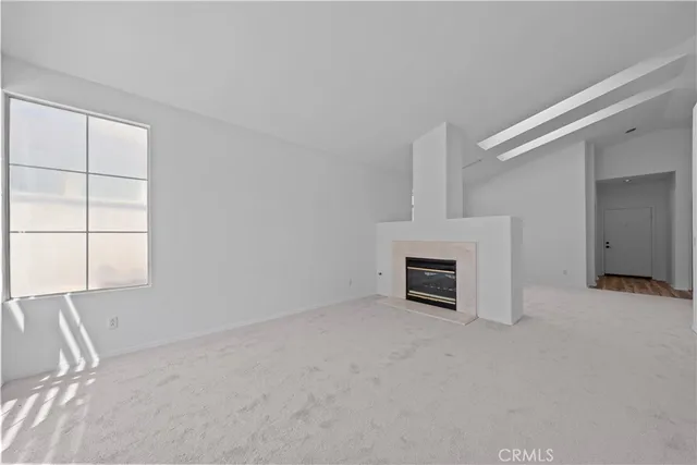 an empty room with windows and fireplace