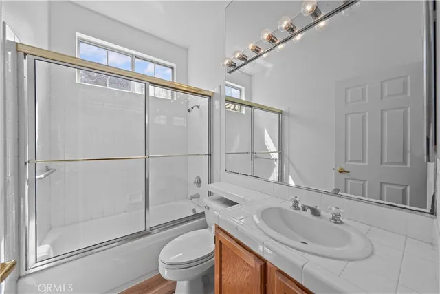 a bathroom with a sink a mirror a toilet and shower