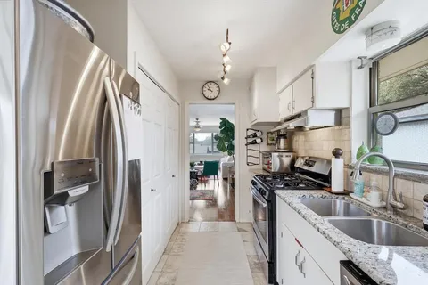 a kitchen with stainless steel appliances granite countertop a sink a stove a refrigerator a washer dryer and a dining table