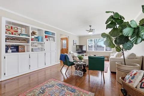 a living room with furniture flowers and wooden floor