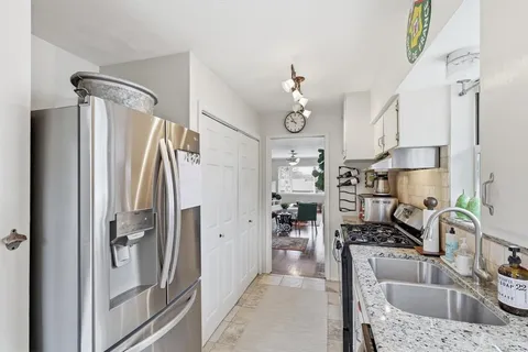 a kitchen with stainless steel appliances granite countertop a refrigerator a sink and white cabinets