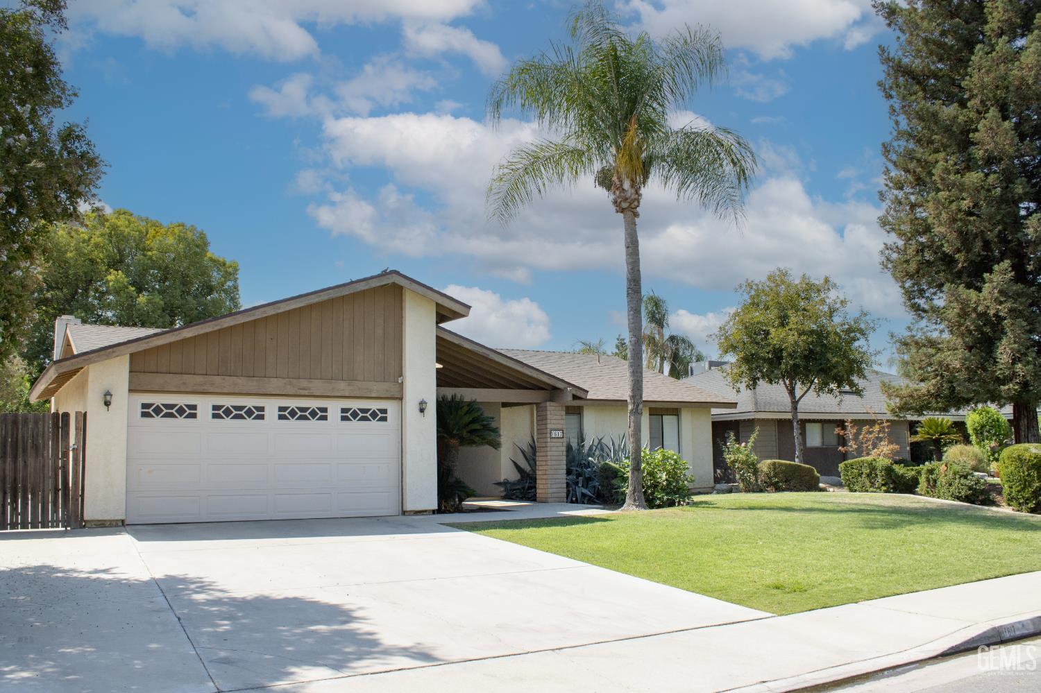 Undisclosed Address Bakersfield, CA 93309 - Photo 2 of 38 a front view of a house with a garden and trees