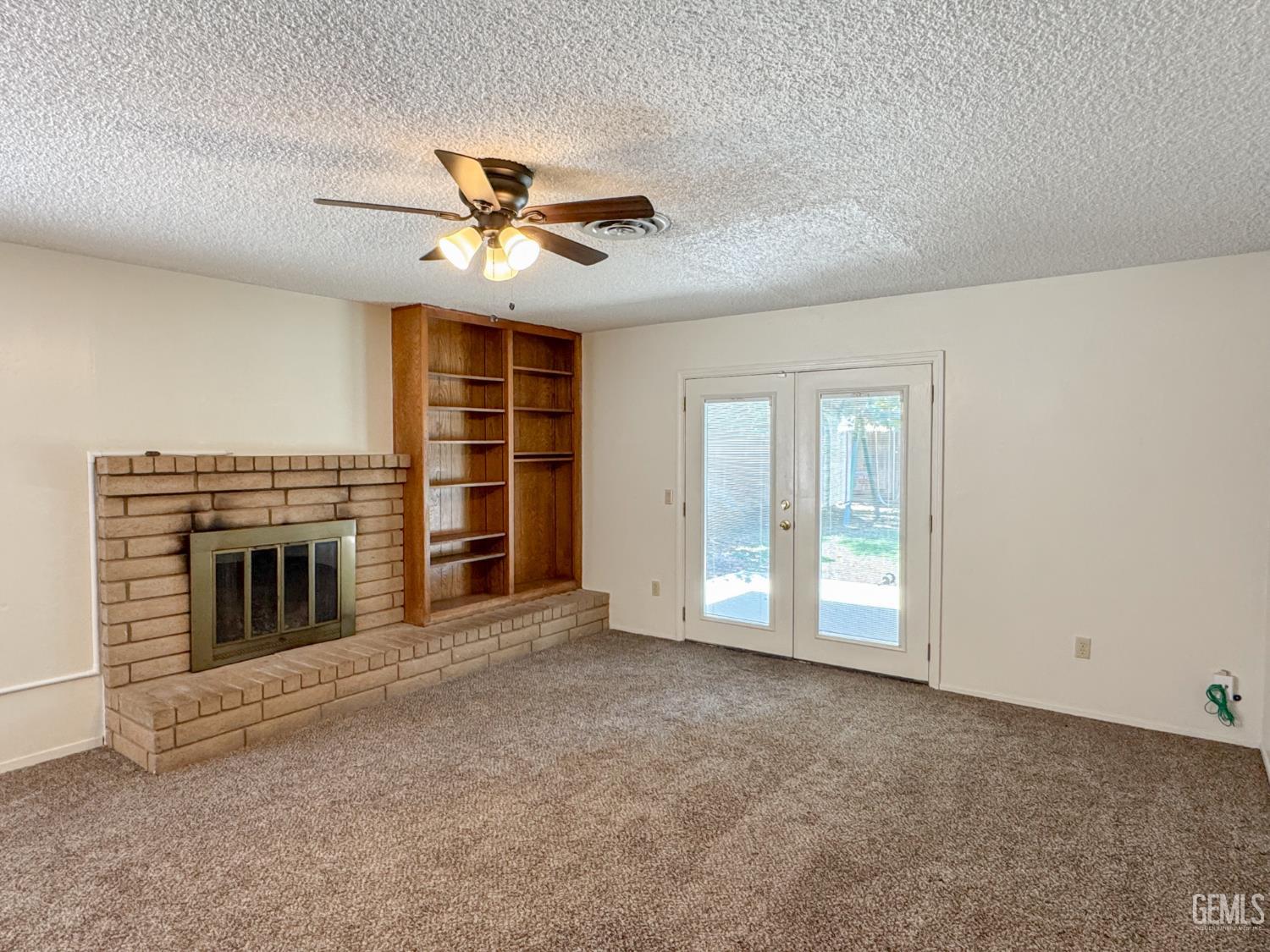 Undisclosed Address Bakersfield, CA 93309 - Photo 7 of 38 a view of an empty room with a fireplace and a ceiling fan
