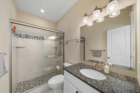a bathroom with a granite countertop sink toilet mirror and shower