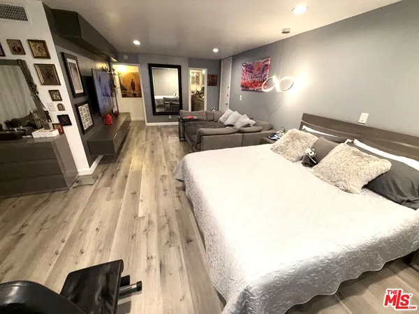 a bedroom with a bed furniture a window and a flat screen tv