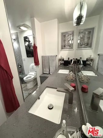 a bathroom with a granite countertop toilet sink and mirror