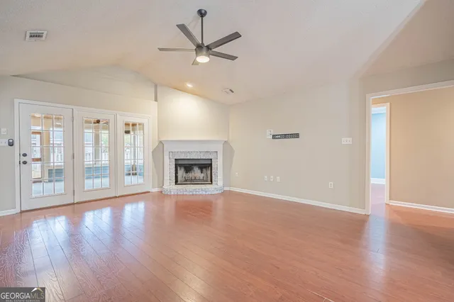 an empty room with wooden floor fireplace and windows