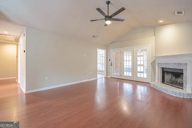 a view of an empty room with wooden floor fireplace and a window