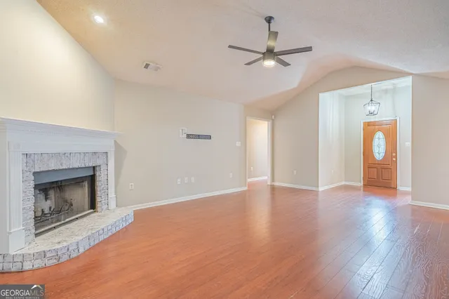 a view of an empty room with wooden floor and windows